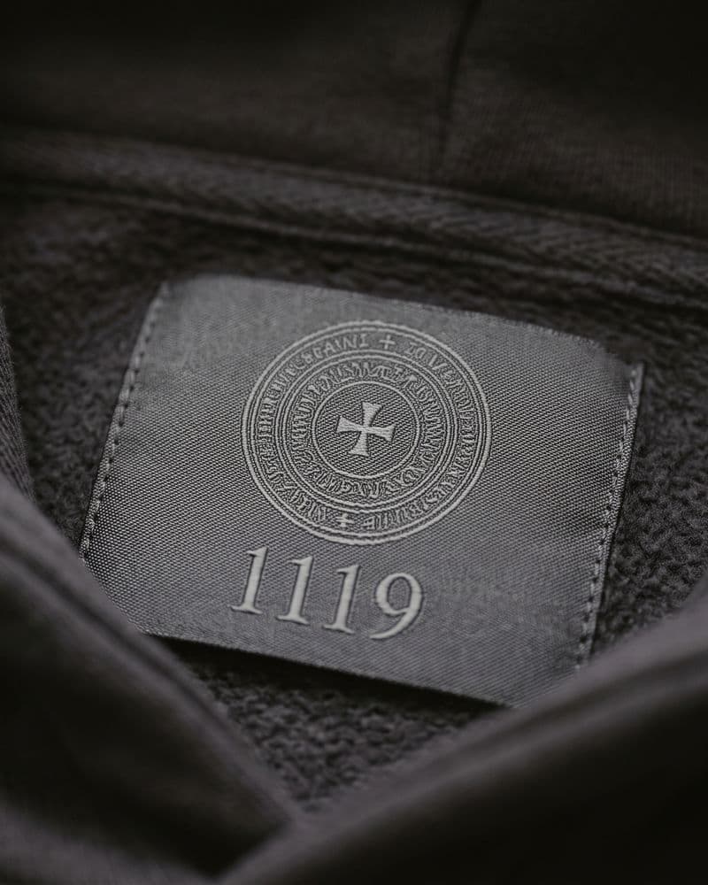 Woven neck label with seal and 1119 inside a charcoal hoodie
